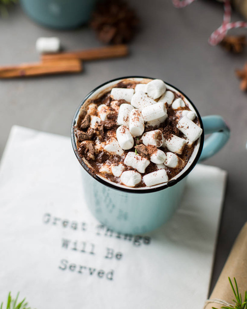 Great things will be served!) Mug of hot chocolate with marshmallow, cinnamon and milk on a gray concrete background with a Christmas tree and gifts. Winter xmas holidays concept. Festive mood.) - Photo, Image