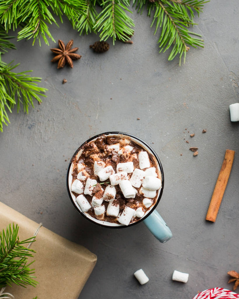 Mug of hot chocolate with marshmallow and cinnamon on gray concrete background with a Christmas tree, gifts. and red-white string (twine). Winter xmas holidays concept. Festive mood.Flat lay, top view - Foto, afbeelding