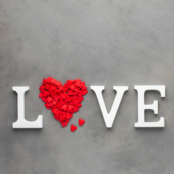 Valentines day background with  red hearts and white letters "LOVE". Sweet candy hearts on a gray concrete background. Romantic mood.) Beautiful background.Flat lay, top view - Photo, Image