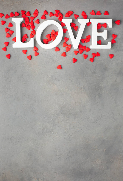Valentines day background with  red hearts and white letters "LOVE". Sweet candy hearts on a gray concrete background. Romantic mood.) Beautiful background.Flat lay, top view - 写真・画像