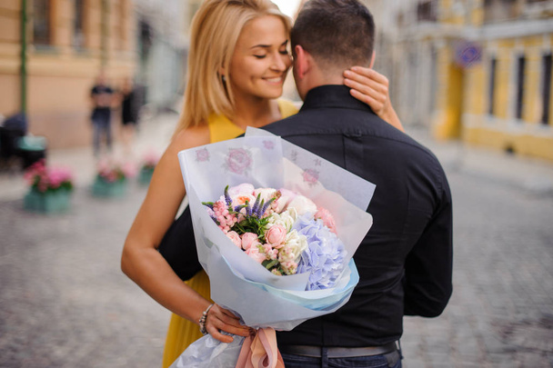girl with a bouquet hugs her boyfriend - Фото, изображение