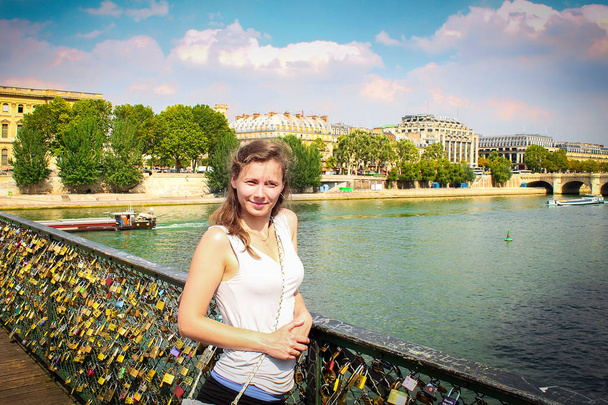 Beautiful young girl on bridge with locks of lovers on river Seine in Paris, bright sunny summer day. Tour of Paris, France - Fotografie, Obrázek