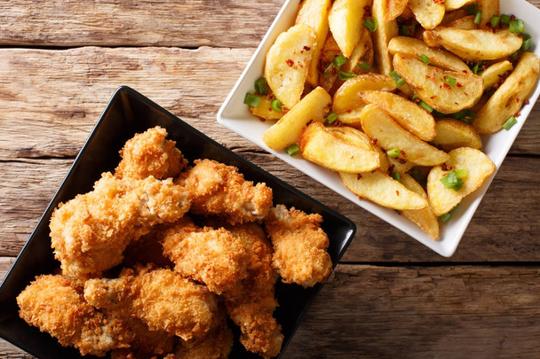 Вкусная еда: жареные куриные крылышки в хлебных крошках и картофеле
 - Фото, изображение