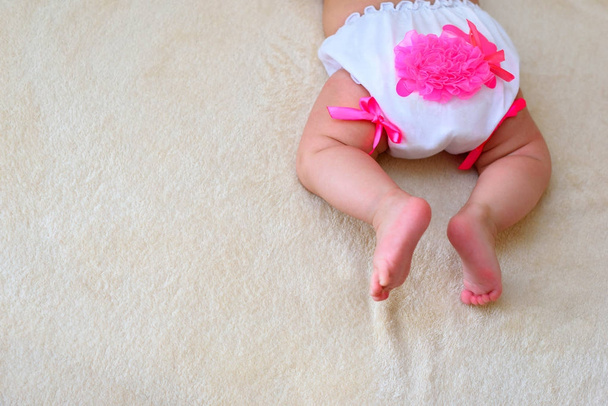 το μωρό στο μικρό λευκό panties ξαπλωμένος σε ένα ομοιογενές φόντο - Φωτογραφία, εικόνα