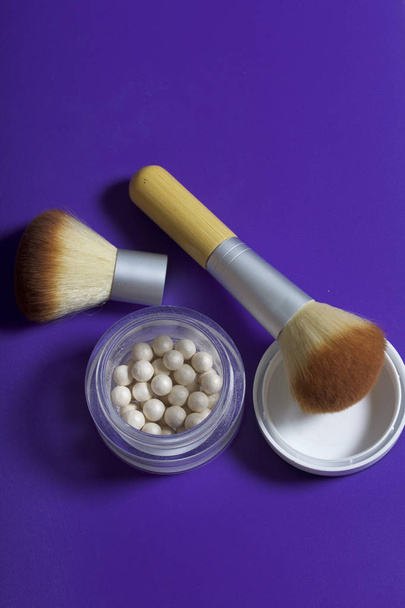 Golden highlighter in the form of balls in an open jar. Next to it is a cosmetic brushes for applying it. - Zdjęcie, obraz