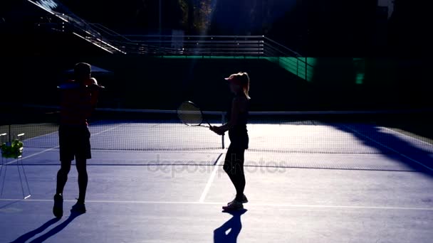 spelers warming-up vóór een spel tennis. Senior man en vrouw tennissen. 4k, silhouetten - Video