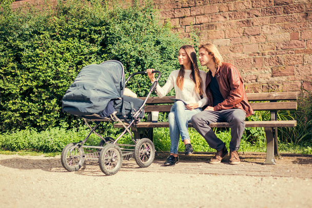 Young Parents With Baby Stroller In The Park - Photo, Image
