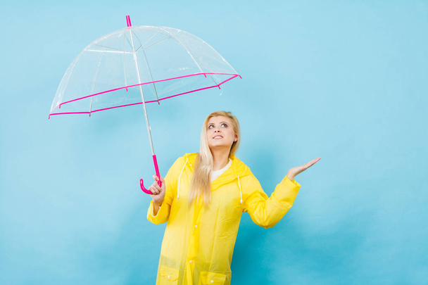 Woman wearing raincoat holding umbrella checking weather - Foto, Imagen