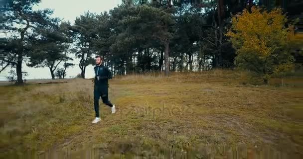 Runner going downhill on a small pathway. Drone flying backwards, zooming out and panning big yellow hill and forest. - Filmmaterial, Video