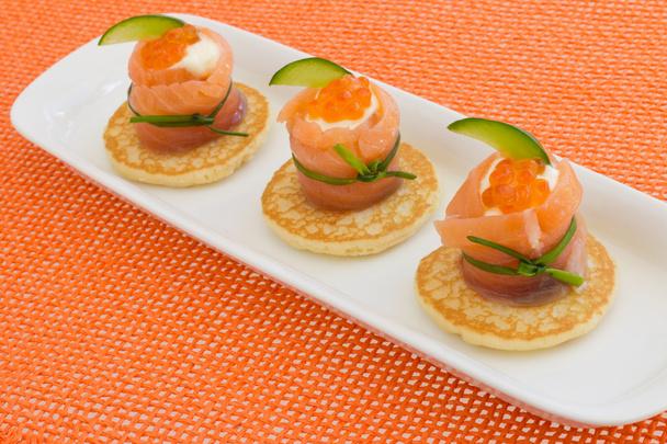 Rollo de salmón rojo con queso, caviar y pepino en blinis
 - Foto, imagen
