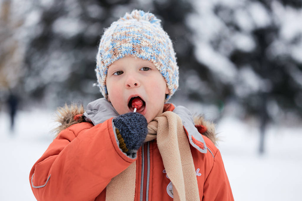 niño en un sombrero de invierno de punto con caramelos de caramelo
. - Foto, imagen