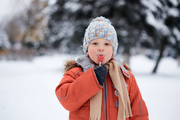 мальчик в вязаной зимней шляпе с конфетками
. - Фото, изображение