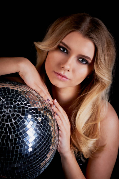 The blonde laying in the style of Abba holds a disco ball. The era of disco.Night club, dancing - Foto, Imagem