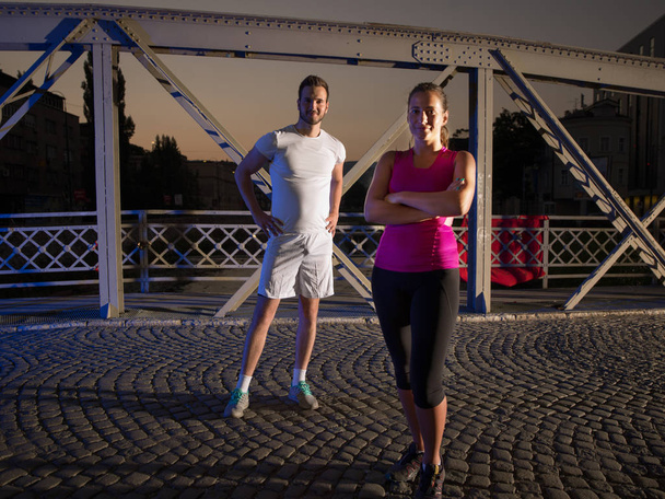 portrait of couple jogging across the bridge in the city - Zdjęcie, obraz