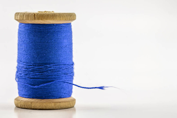 Котушка або котушка синьої швейної нитки ізольовані на білому. Неглибокий d
 - Фото, зображення