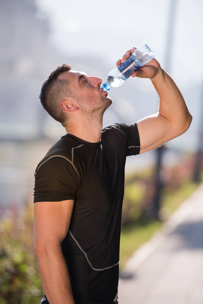 man drinking water from a bottle after jogging - Photo, Image