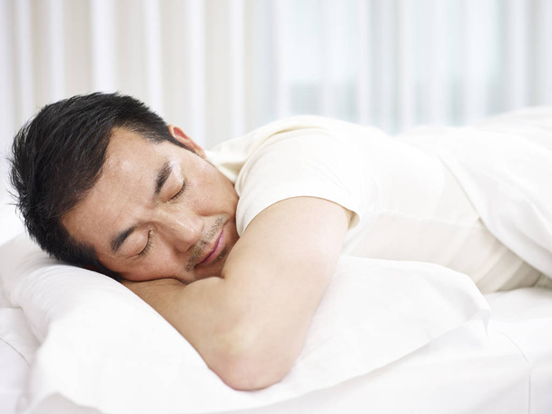 azjatycki człowiek śpi w łóżku - Zdjęcie, obraz