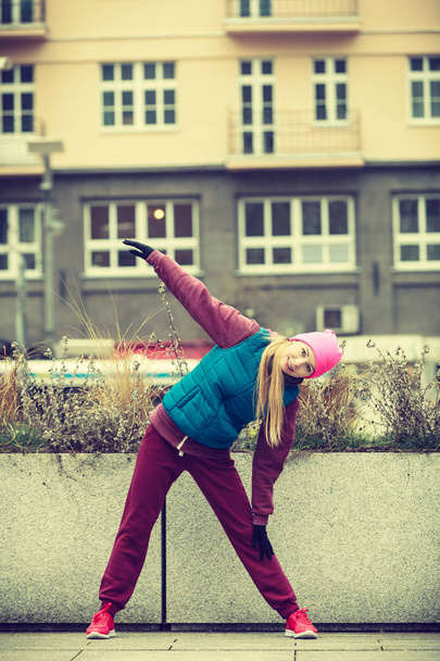 Sporty girl stretching outdoor on city street. - Foto, afbeelding