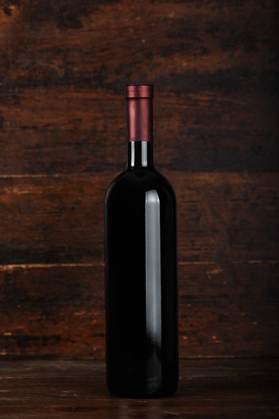 closed bottle of wine on a wooden background - Photo, Image