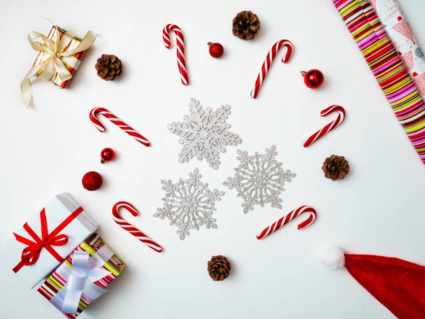 Joyful christmas background. Beautiful present boxes, traditional candy cane lollipops, snowflakes, Santa hat. Preparing for winter holidays concept, top view, copy space - Photo, image