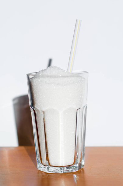 Glass with sugar and straw as symbol of unhealthy diet. - Foto, Imagem