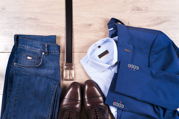 conjunto de roupas masculinas clássicas - terno azul, camisas, sapatos castanhos, cinto e gravata em fundo de madeira. - Foto, Imagem