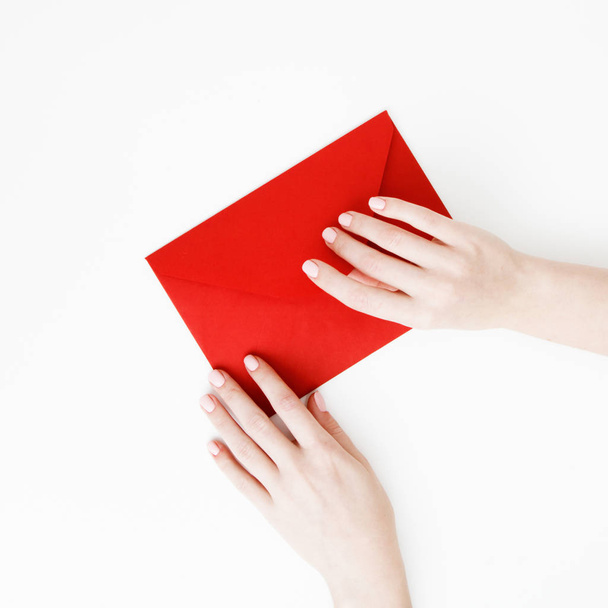 Flat lay. Top view. A minimalistic style of fashion and beauty photography. Hands holding craft paper gift envelope with as a present for Christmas, new year, valentine day or anniversary - Photo, Image