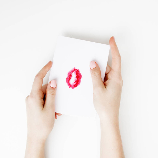 Επίπεδη θέσει. Το Top view. Το χέρι του κοριτσιού εγγράφως επιστολή αγάπης για Αγίου Βαλεντίνου. Χειροποίητα καρτ ποστάλ με κόκκινα χείλη σε σχήμα σχήμα. Γυναίκα κλήρωση φιλί στο καρτ ποστάλ για 14 Φεβρουαρίου εορτής - Φωτογραφία, εικόνα