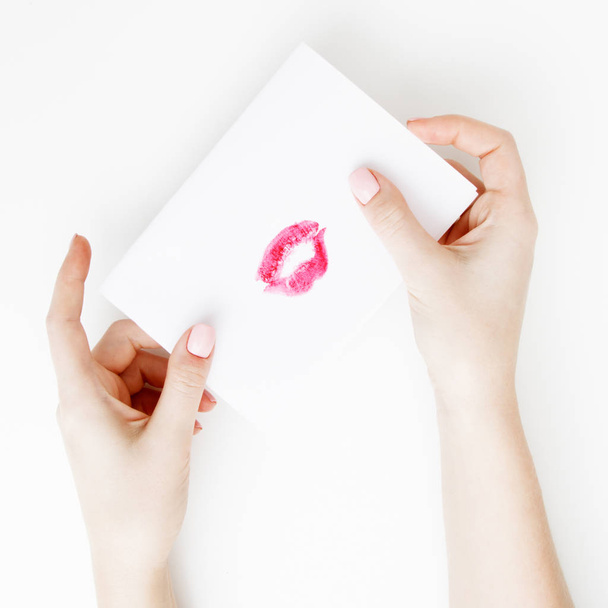 Flat lay. Top view. Hand of girl writing love letter on Saint Valentines Day. Handmade postcard with red lips shaped figure. Woman draw kiss on postcard for 14 February holiday celebration - Φωτογραφία, εικόνα