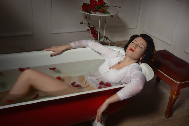 Hermosa mujer sexy en baño vintage con pétalos de flores
 - Foto, Imagen