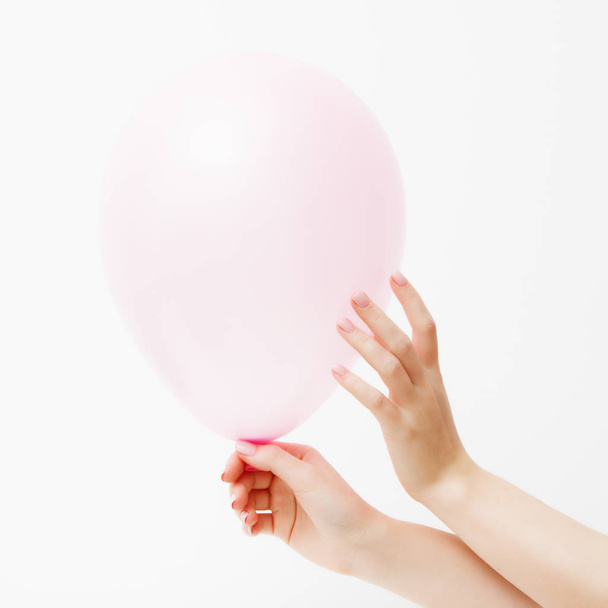 Moda minimalista y foto de belleza. Mano sosteniendo un globo rosado sobre un fondo de pared blanco con reflejo de sombra. El concepto de San Valentín o cumpleaños. 14 de febrero
 - Foto, Imagen