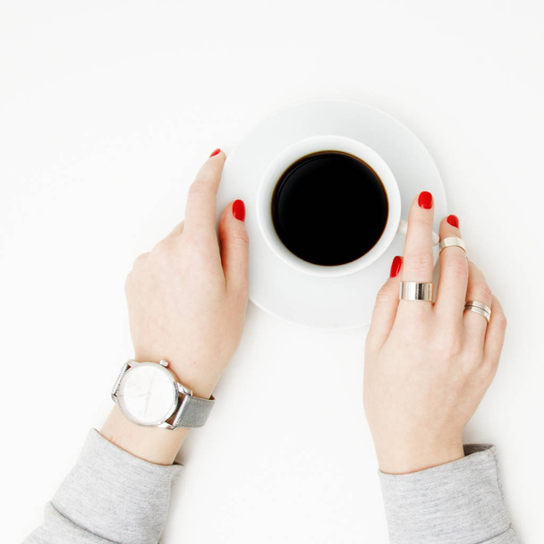 Flat lay. Top view. Minimal style. Minimalist Fashion and beauty photography. Morning mood. A girl in a sweater manicure holds a white cup of coffee on a white table background. Watches and jewelry - Photo, Image