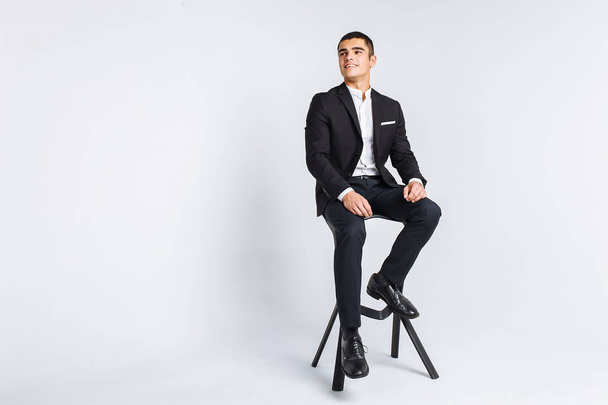 Portrait of the beautiful posing in a Studio, White background, Stylish business man, Stylish man sitting on a designer chair - Photo, image