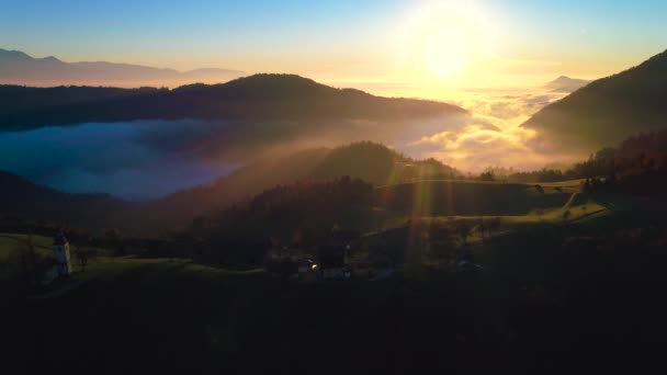 Sonnenaufgang Luftaufnahme der Kirche Saint Tomas, Slowenien. schönes Tal mit grünen Weiden. Panoramalandschaft - Filmmaterial, Video