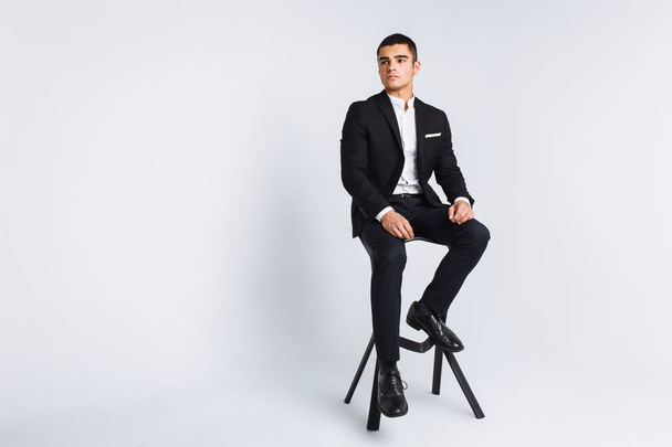 Portrait of the beautiful posing in a Studio, White background, Stylish business man, Stylish man sitting on a designer chair - Фото, изображение