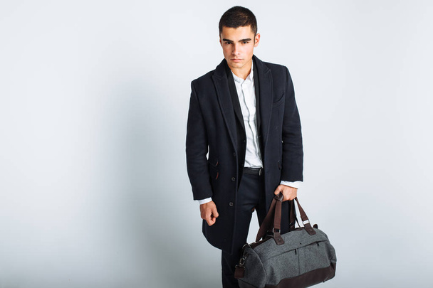 Stylish man in Studio on a white background, with a bag for travel, isolated, background, man goes on a journey - Fotó, kép