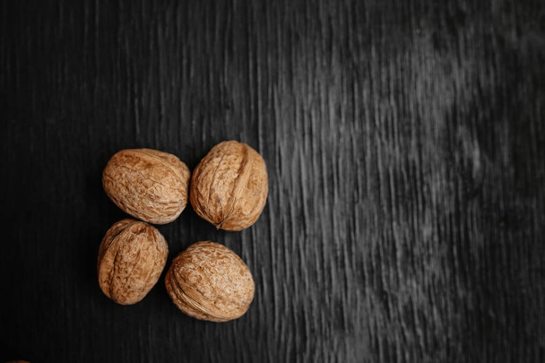 Lots of fresh nuts on a black wooden background. Best practices for designer. A beautiful design from the nuts - Foto, imagen