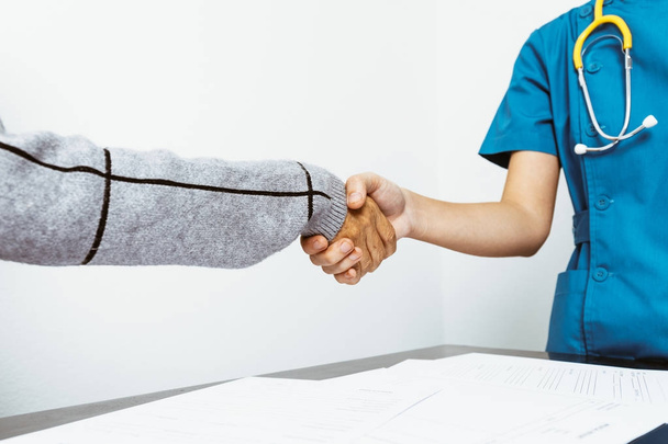 Jovem enfermeira apertando as mãos com paciente mulher sênior após therap
 - Foto, Imagem