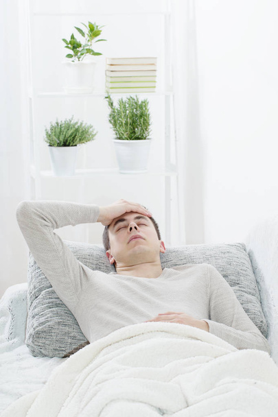 a man with a headache on the sofa - Фото, изображение