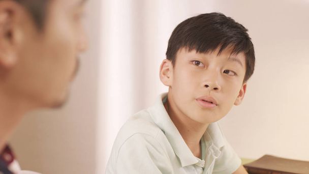 Aasialainen isä puhuu & neuvonta hänen turhautunut teini poika kotona
 - Valokuva, kuva