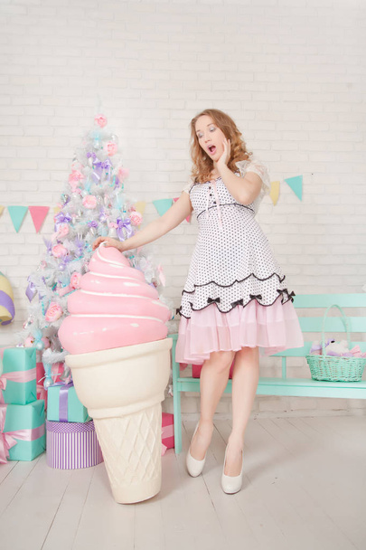 мила дівчина-підліток у милій сукні навколо ялинки з подарунками та величезними цукерками
 - Фото, зображення