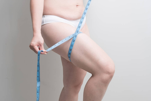 Fat overweight woman measuring  her leg - Photo, image
