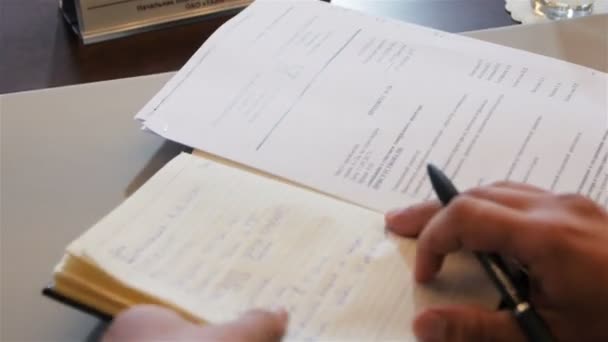 closeup upper view businessman opens notebook with leather cover and writes new task with pen at office table - Filmmaterial, Video