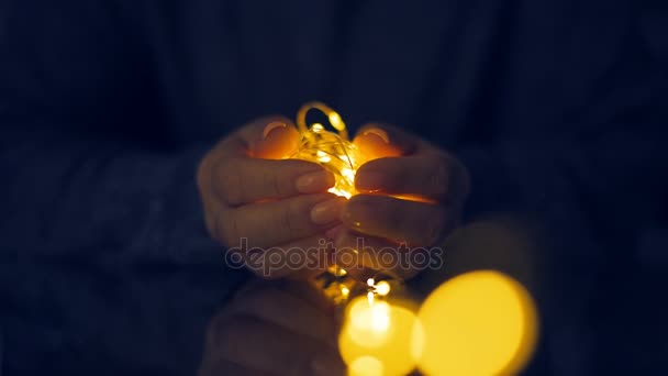 Female hands hold garlands of lights . - Imágenes, Vídeo