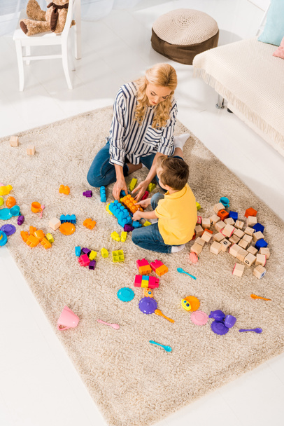 high angle view of mother and little son playing with toys together on floor at home - Photo, Image