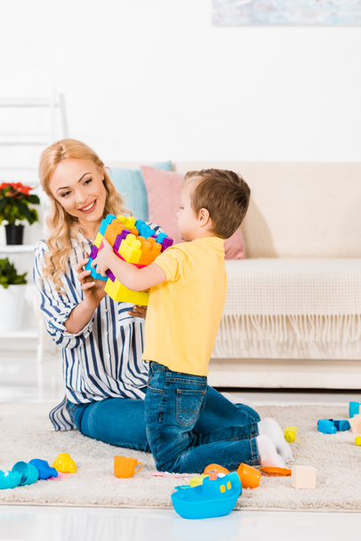 mãe e pequeno filho brincando com brinquedos juntos no chão em casa
 - Foto, Imagem