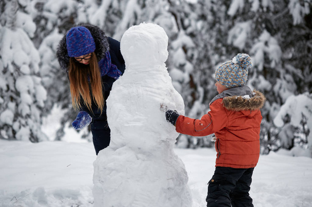 zimní radovánky. dívka a chlapec dělat sněhové koule. - Fotografie, Obrázek