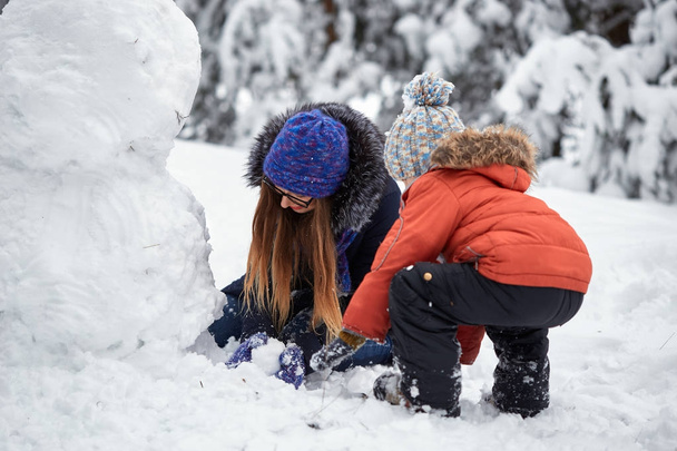 διασκέδαση χειμώνα. ένα κορίτσι και ένα αγόρι κάνοντας χιονόμπαλες. - Φωτογραφία, εικόνα
