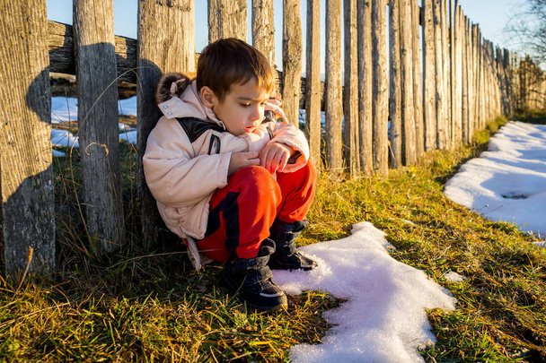 Niño en la nieve junto a la valla de madera
 - Foto, imagen