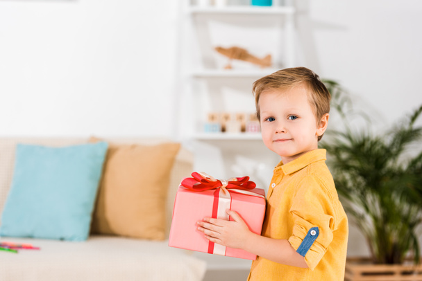 side view of little boy holding wrapped present in hands - Foto, Bild